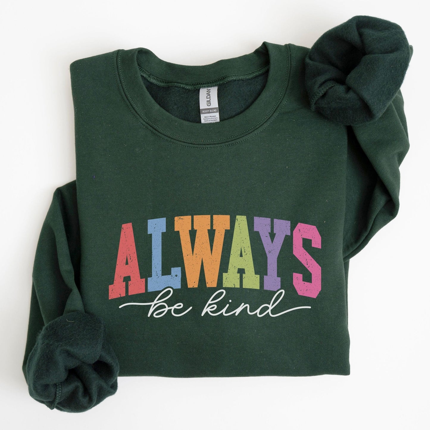 Retro rainbow “Always Be Kind” sweatshirt design with bold varsity letters in pastel colors and script font underneath on a cozy fleece pullover.