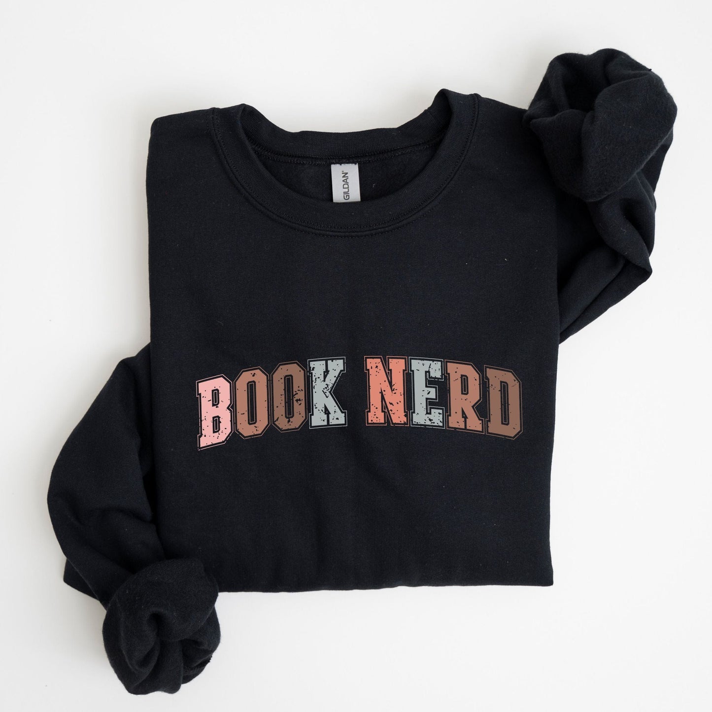 “Book Nerd” sweatshirt with retro textured lettering in muted tones — cozy crewneck for book lovers and casual vintage style.