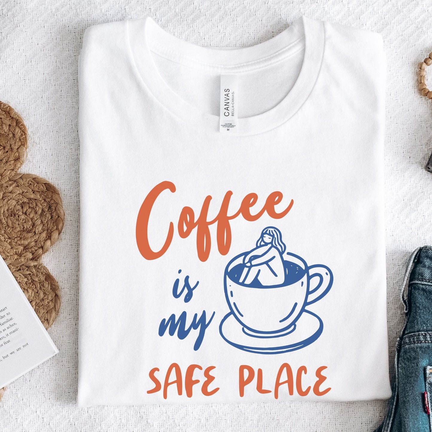 Blue and orange graphic t-shirt with text “Coffee is my safe place” featuring a girl sitting inside a coffee cup illustration.