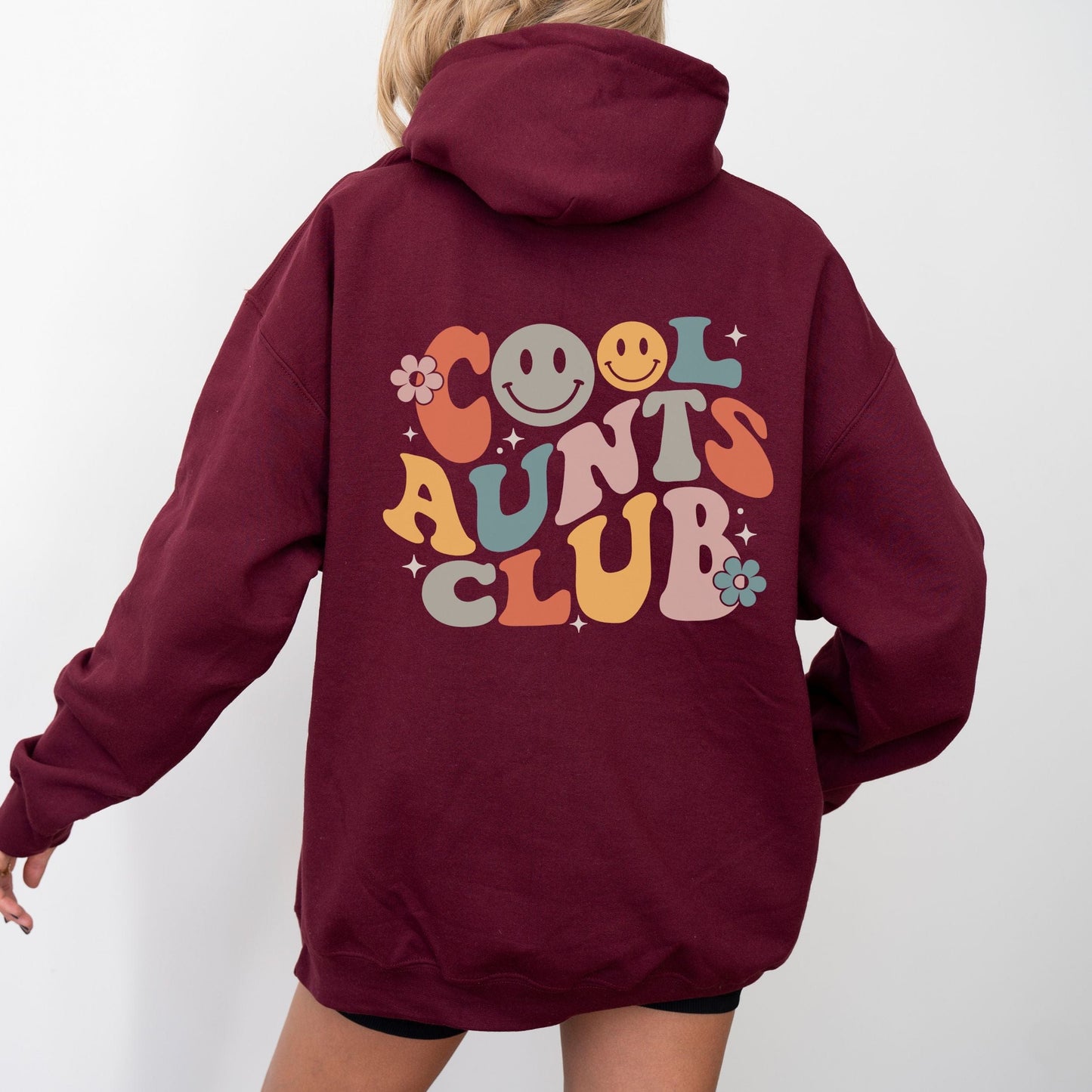 Retro multicolor “Cool Aunts Club” graphic with smiley faces and flowers on the back of a hoodie