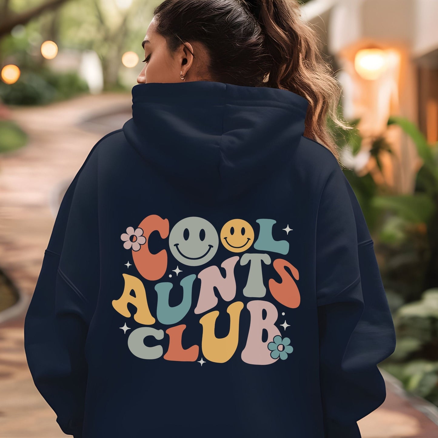 Retro multicolor “Cool Aunts Club” graphic with smiley faces and flowers on the back of a hoodie