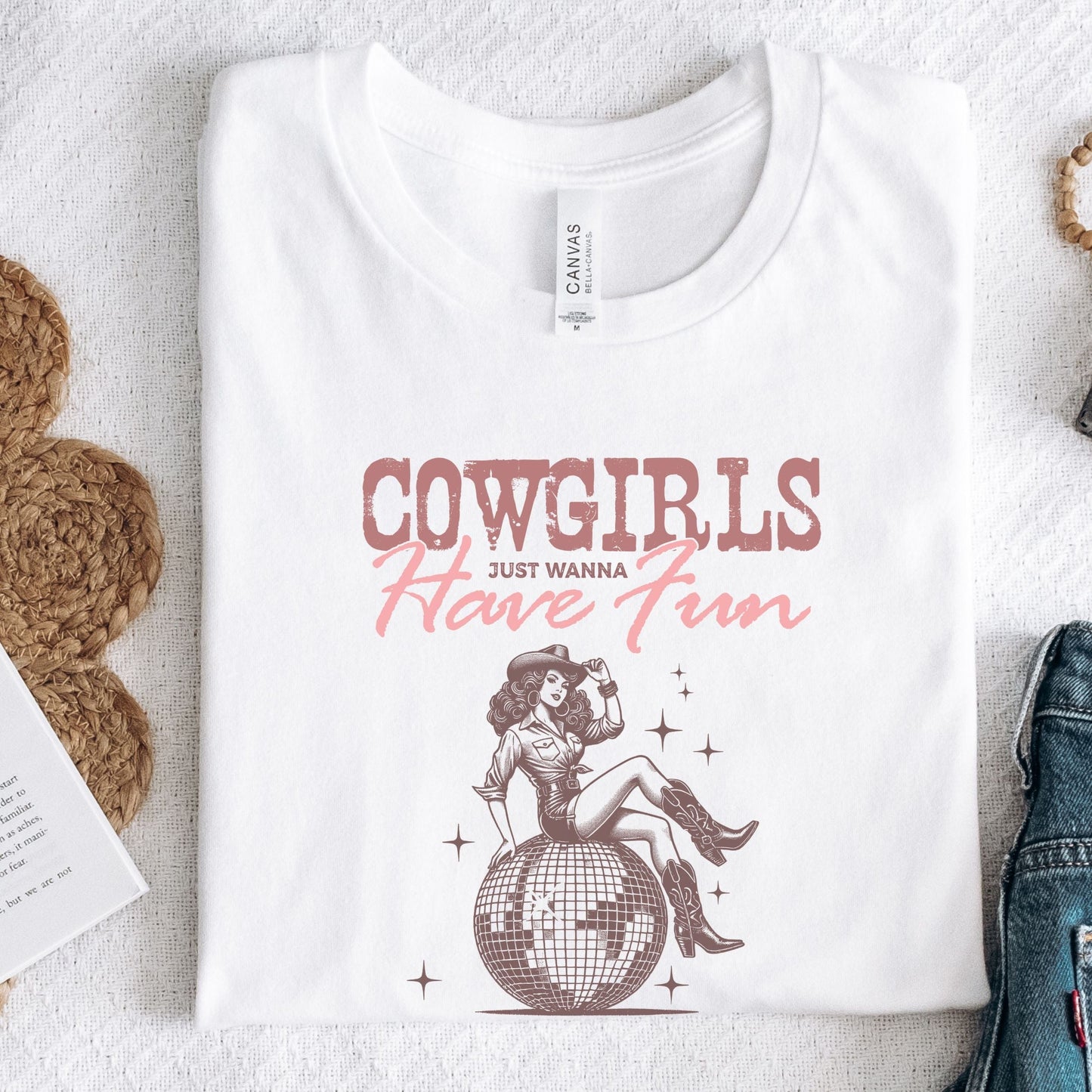T-shirt featuring retro cowgirl design with “Cowgirls Just Wanna Have Fun” text in pink