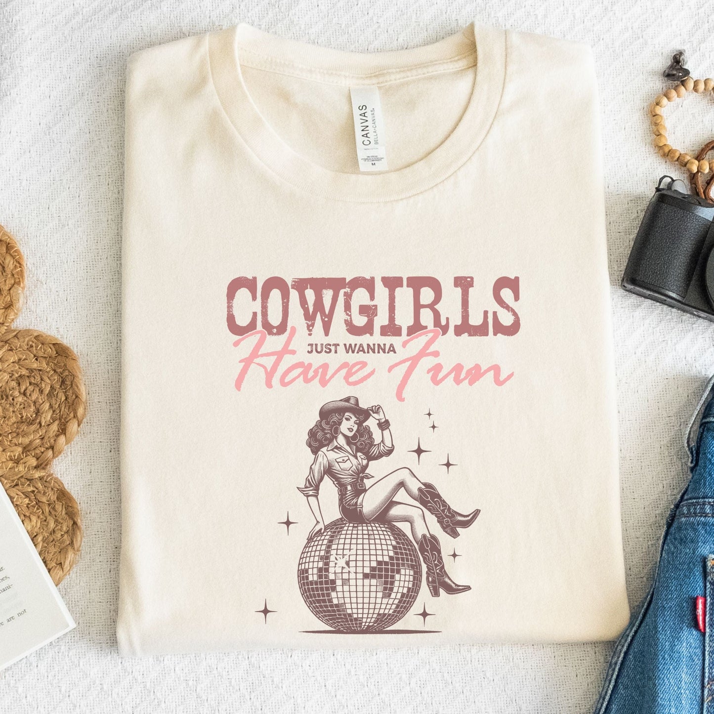 T-shirt featuring retro cowgirl design with “Cowgirls Just Wanna Have Fun” text in pink