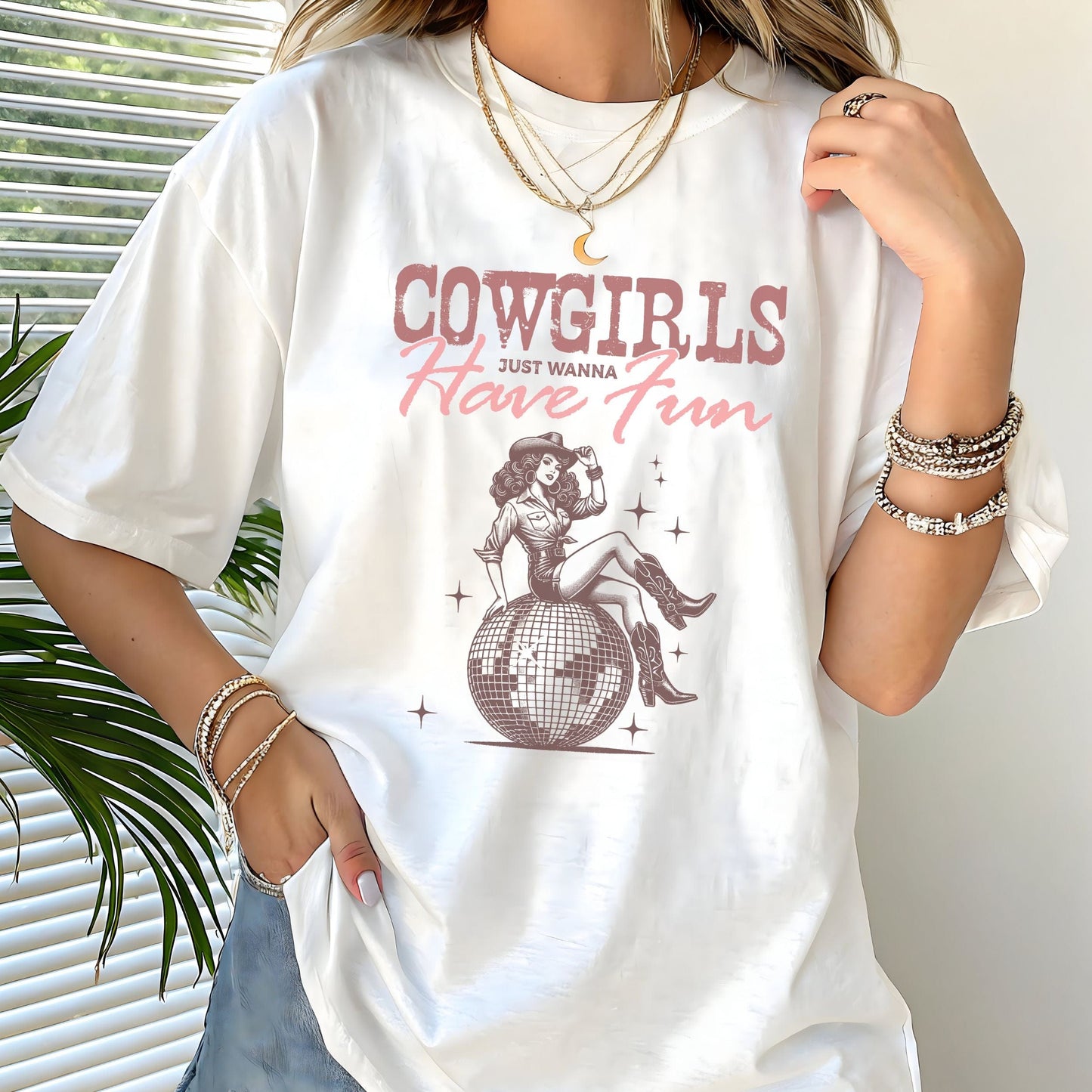 T-shirt featuring retro cowgirl design with “Cowgirls Just Wanna Have Fun” text in pink