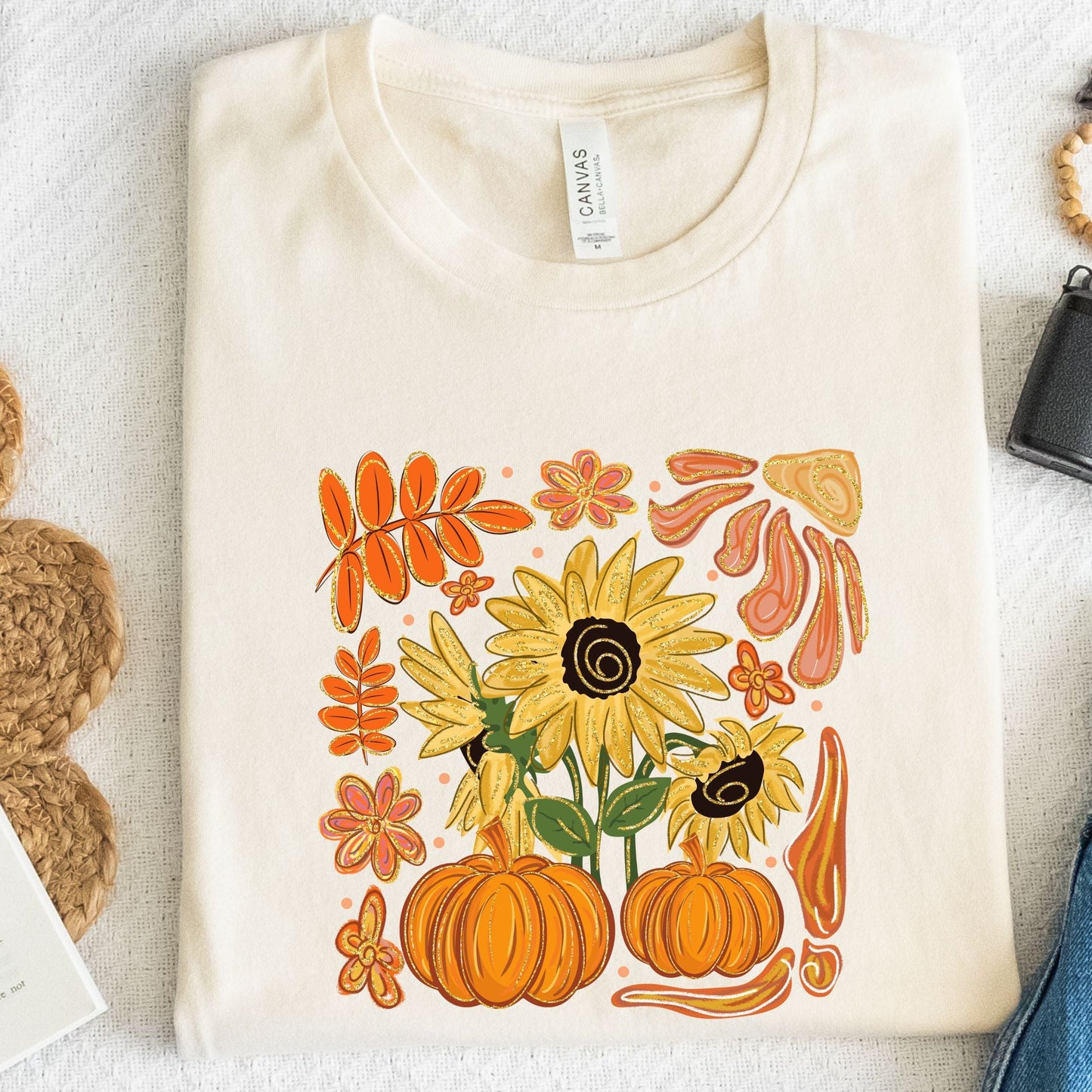 Natural t-shirt with autumn-themed design featuring sunflowers and pumpkins on a textured surface.