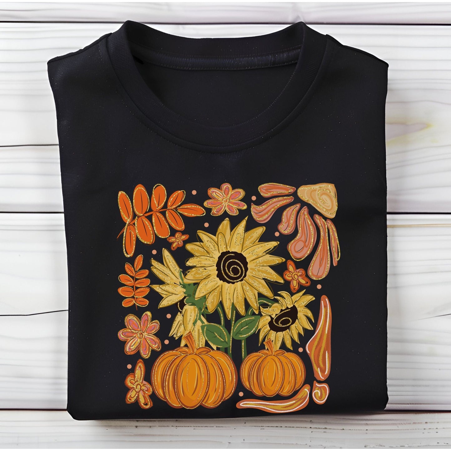 Black t-shirt with autumn-themed design featuring sunflowers, pumpkins, and leaves on a wooden surface.
