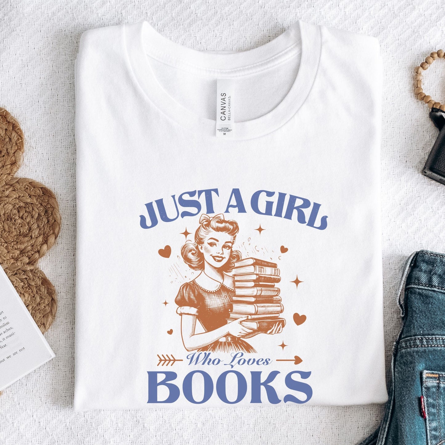 Vintage-style graphic tee that says "Just a Girl Who Loves Books" with a retro girl holding a stack of books and heart accents.