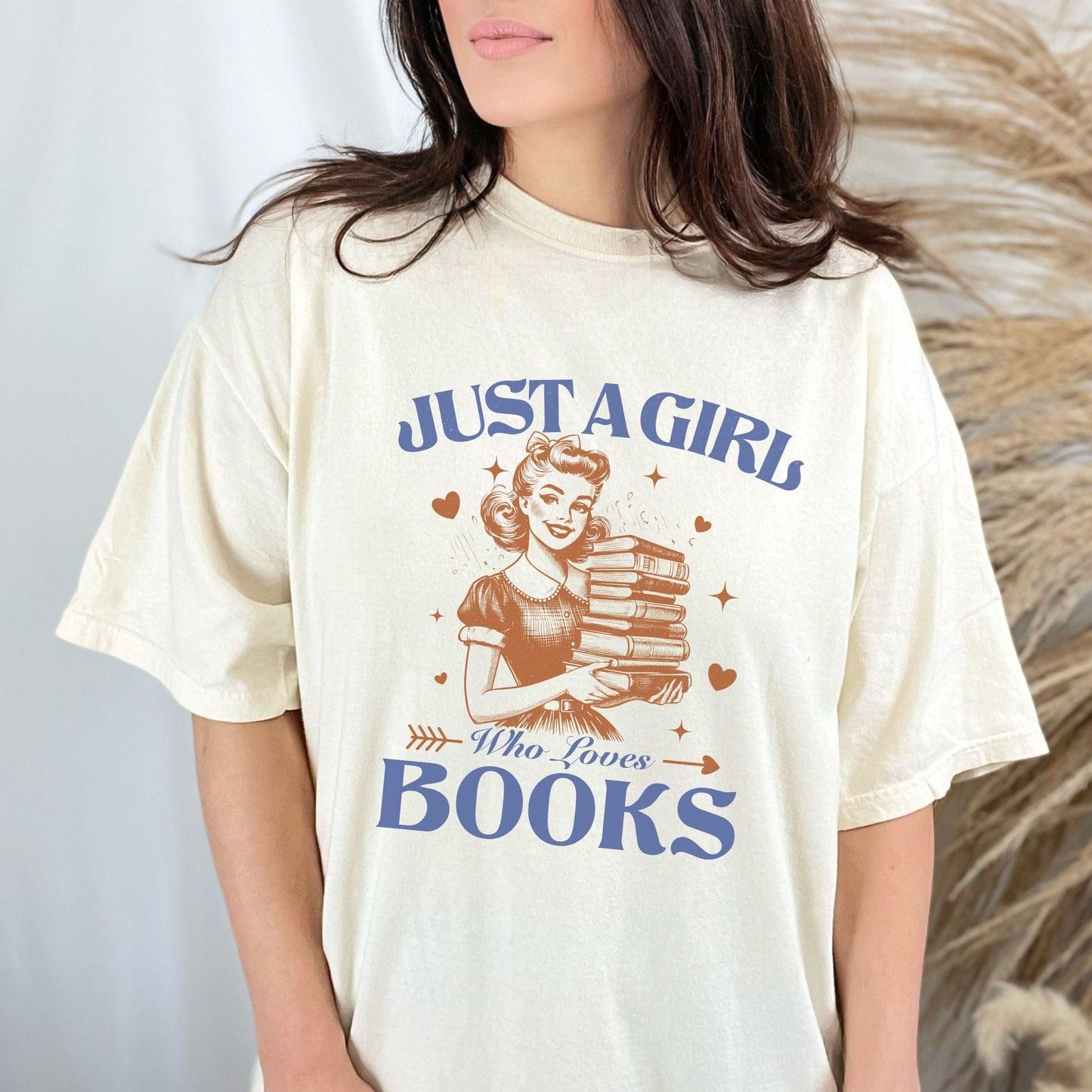 Vintage-style graphic tee that says "Just a Girl Who Loves Books" with a retro girl holding a stack of books and heart accents.