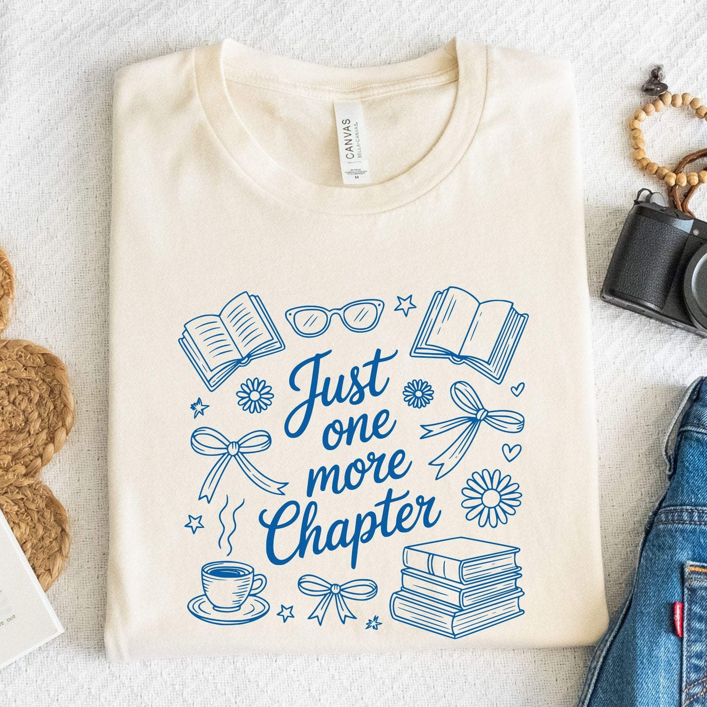 Just One More Chapter t-shirt in a cozy book lover aesthetic with bows, books, and daisies on front design