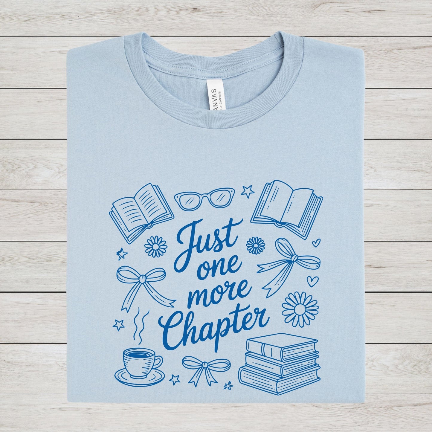 Just One More Chapter t-shirt in a cozy book lover aesthetic with bows, books, and daisies on front design