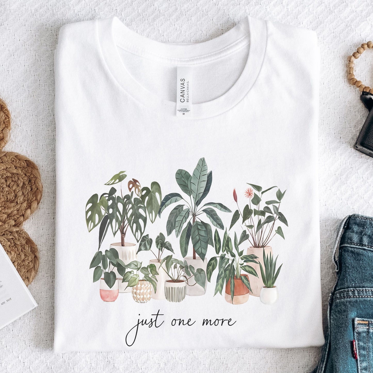 T-shirt with potted houseplants in watercolor style — monstera, rubber plant, snake plant, and more on a black background.