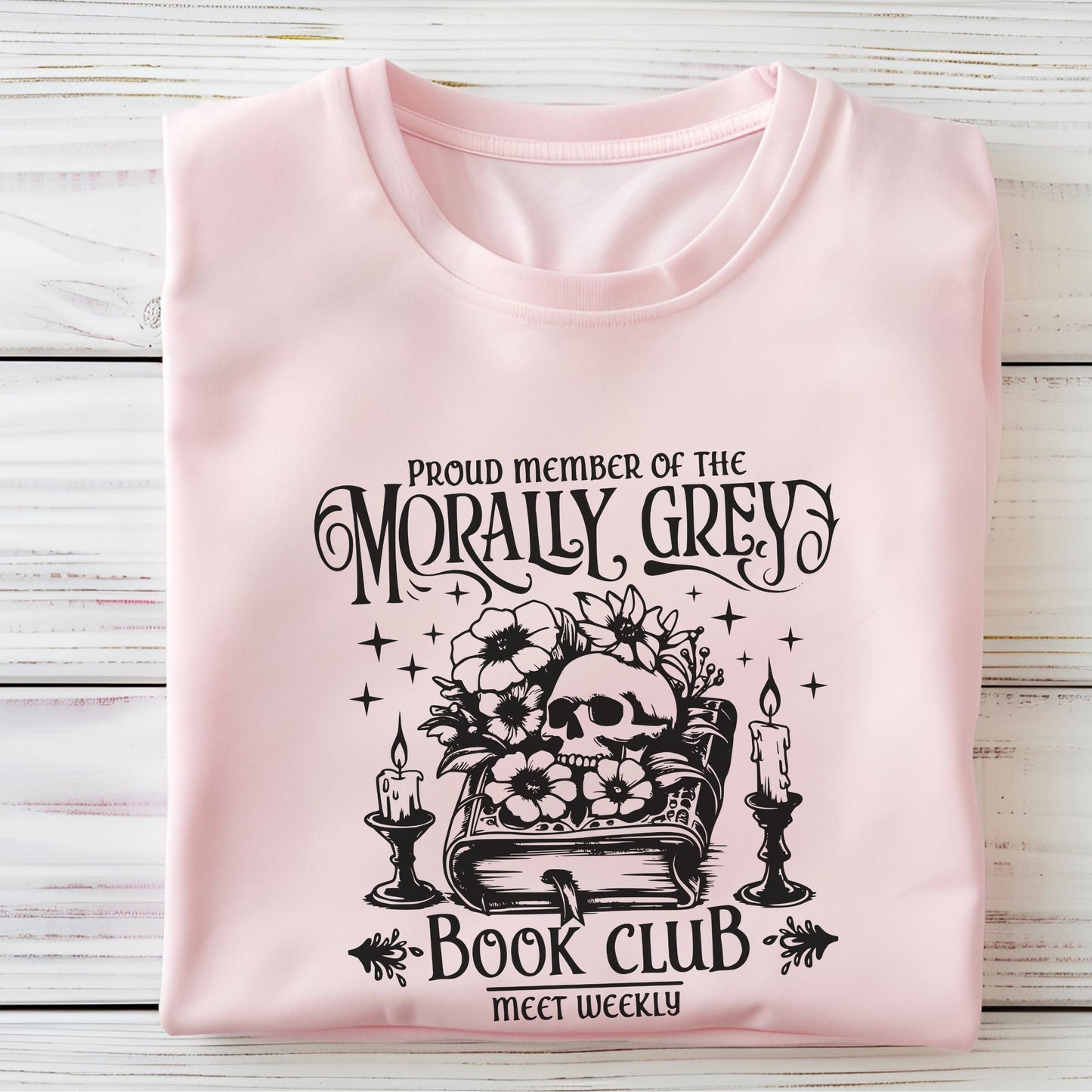 Folded t-shirt with dark fantasy-style text design in soft pink