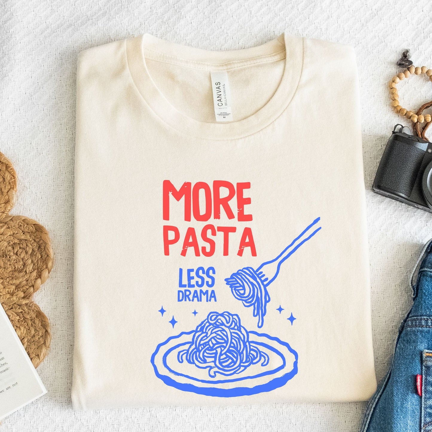 T-shirt with a plate of spaghetti and fork illustration and “More Pasta, Less Drama” text in natural