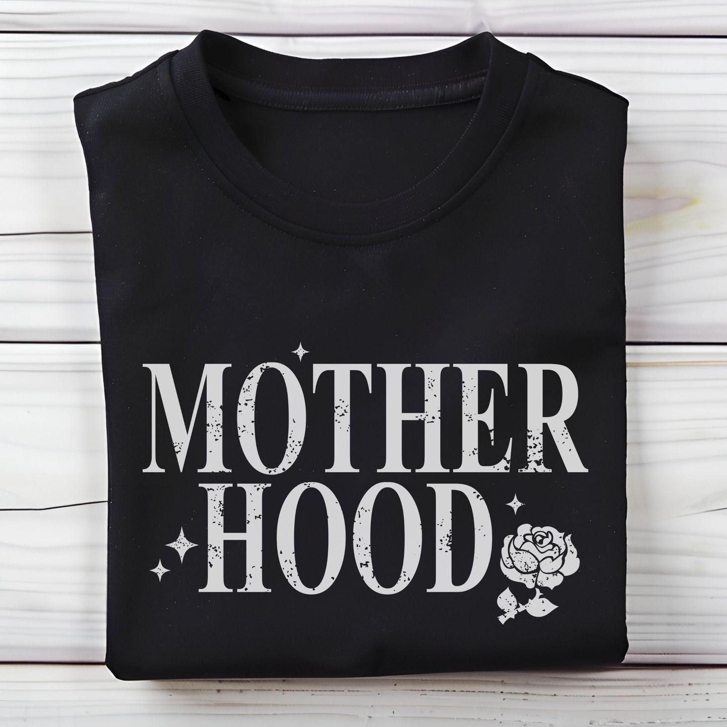 T-shirt with “Motherhood” text in distressed font and floral graphic. A soft, meaningful gift tee for moms.