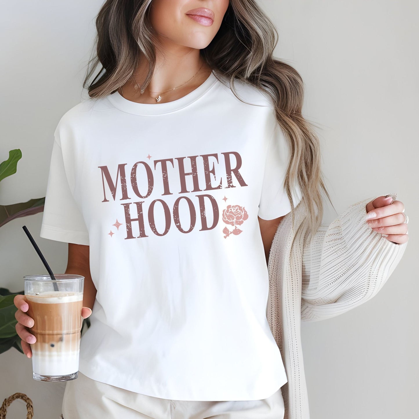 T-shirt with “Motherhood” text in distressed font and floral graphic. A soft, meaningful gift tee for moms.