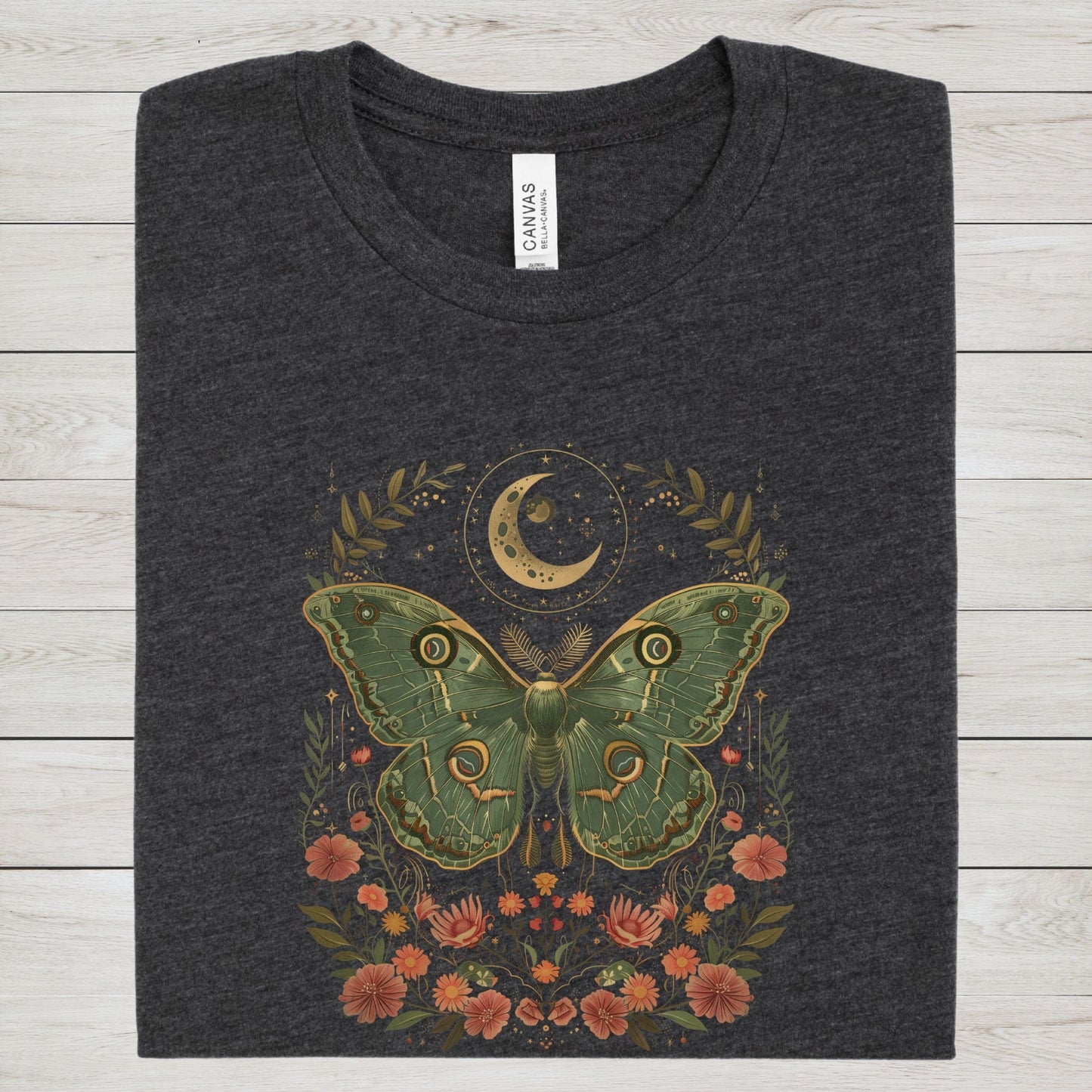 T-shirt design featuring a green luna moth with moon and stars above, surrounded by whimsical flowers and botanical elements in a cottagecore style