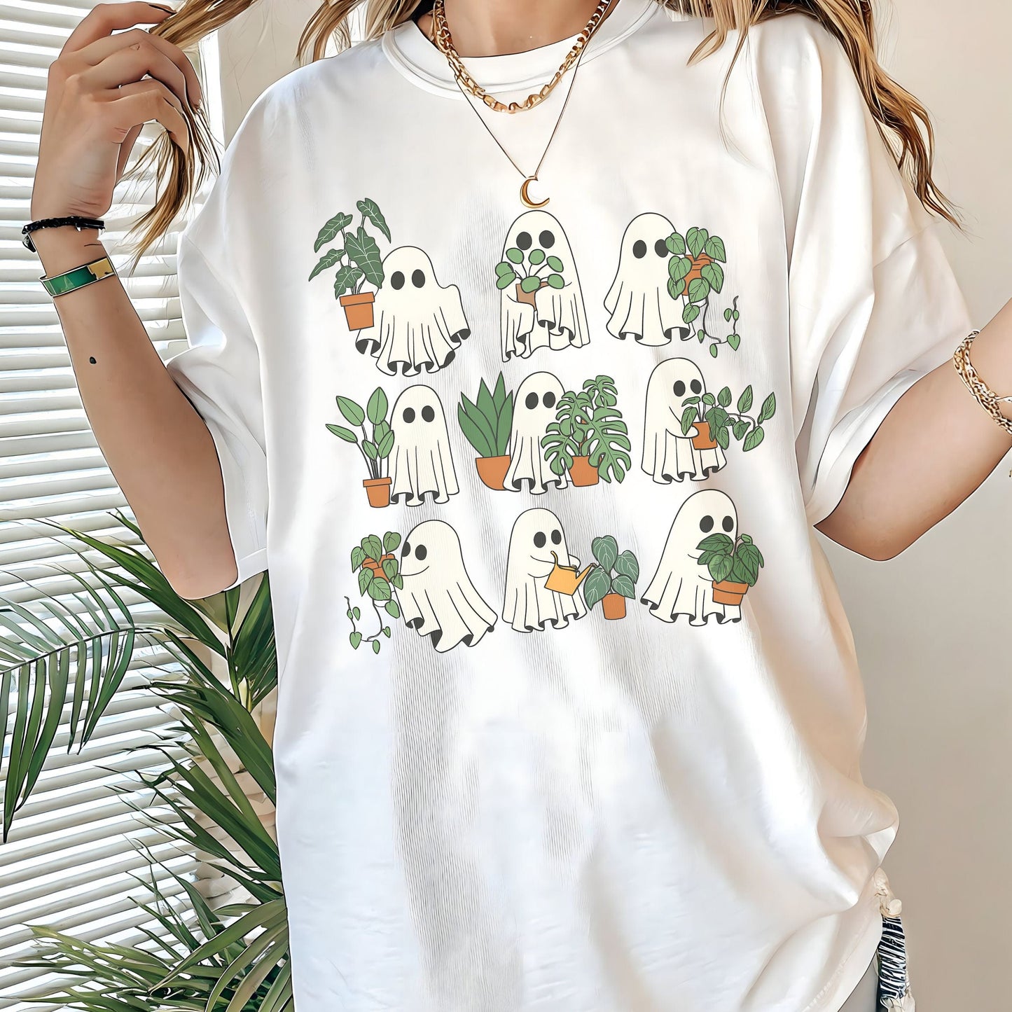 White t-shirt with ghost and plant design worn by a person, with plants in the background