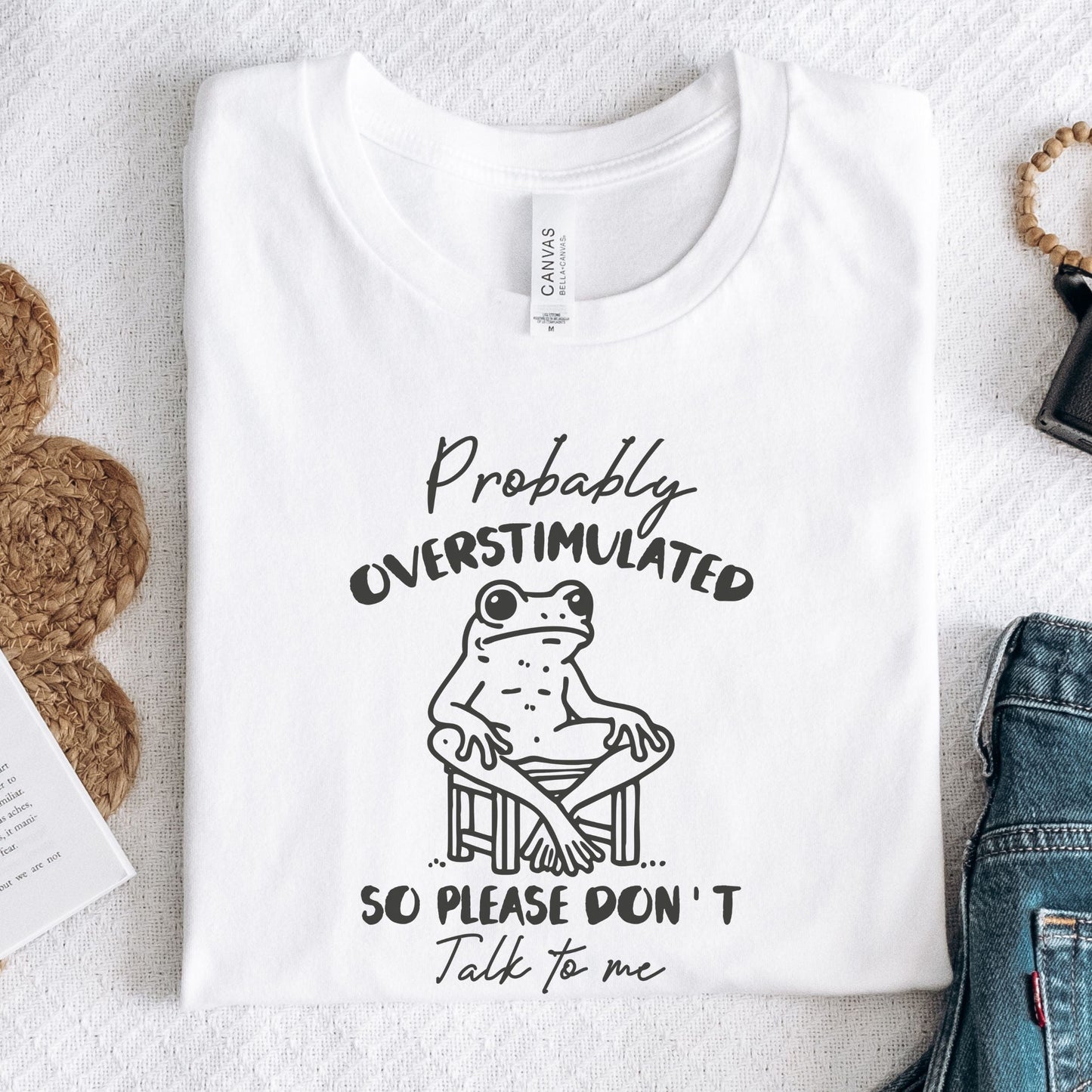 T-shirt with a cute frog illustration and "Probably Overstimulated" quote in hand-drawn font in white