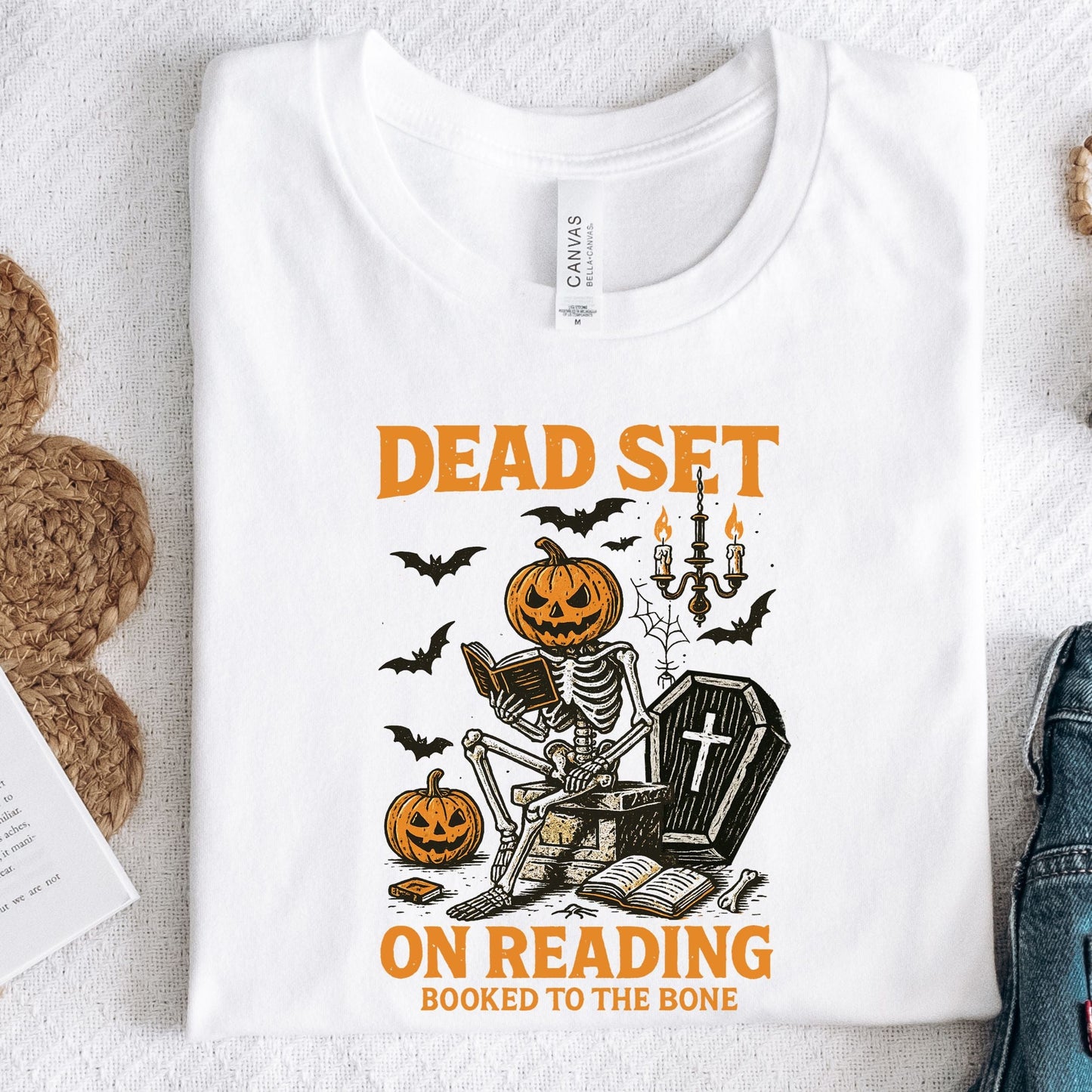 Vintage Halloween t-shirt with a skeleton reading a book, pumpkin head, bats, and spooky autumn vibe
