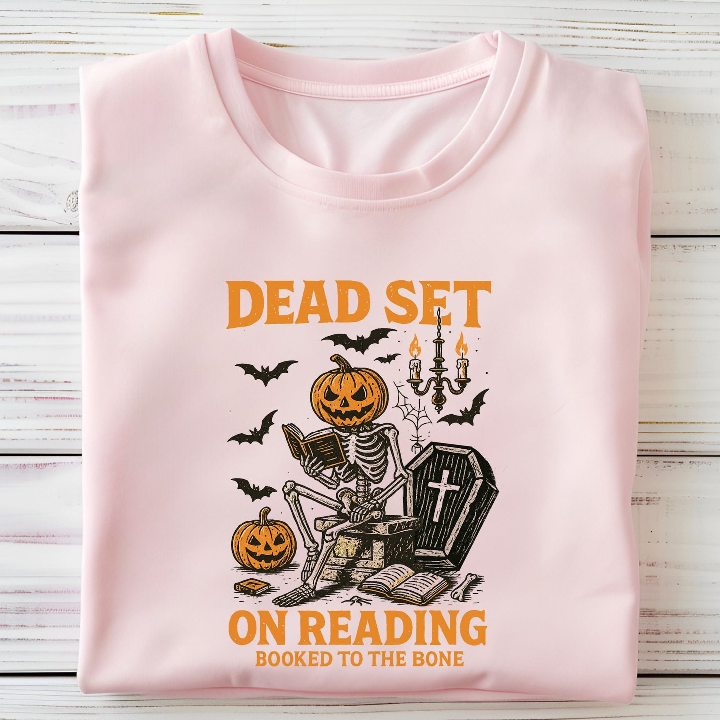 Vintage Halloween t-shirt with a skeleton reading a book, pumpkin head, bats, and spooky autumn vibe