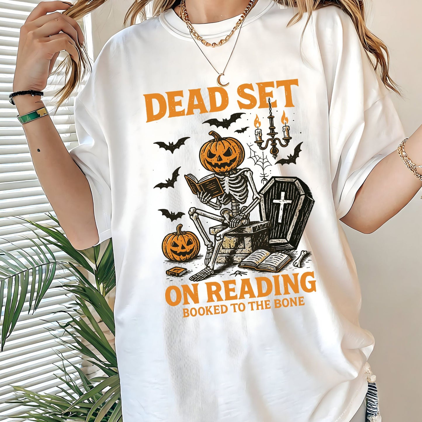 Vintage Halloween t-shirt with a skeleton reading a book, pumpkin head, bats, and spooky autumn vibe