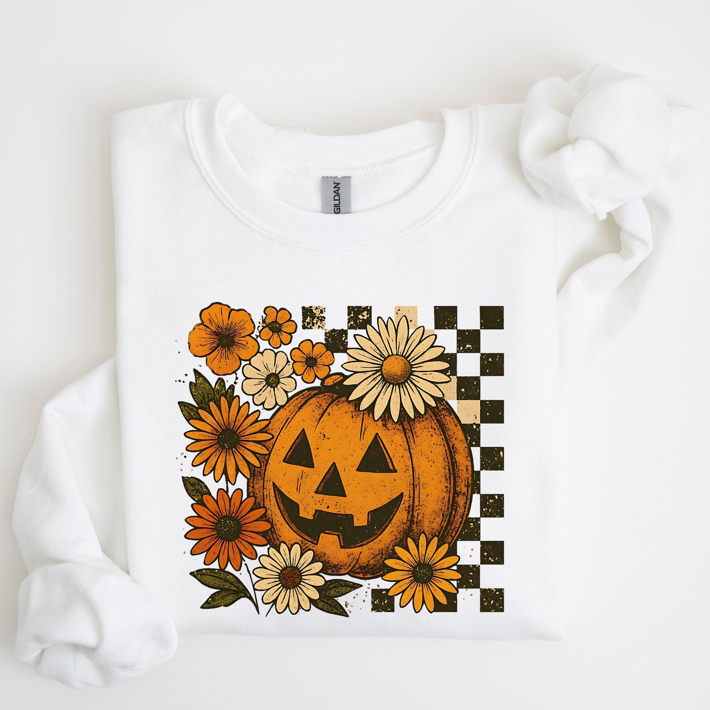 White sweatshirt with a Halloween-themed design featuring a jack-o'-lantern and flowers on a white background.