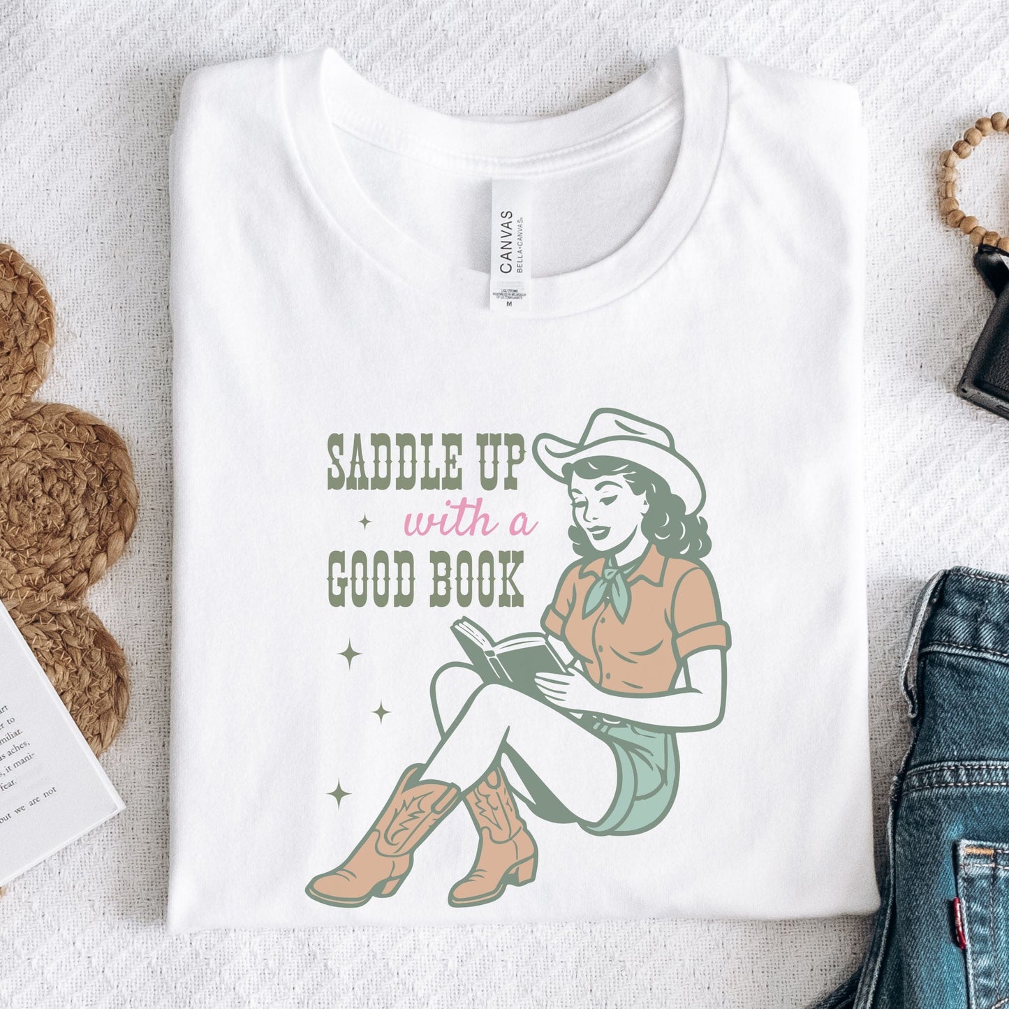 Folded t-shirt with Saddle Up With A Good Book design in white