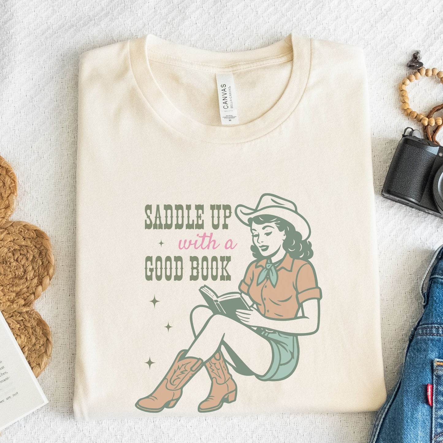 Folded t-shirt with Saddle Up With A Good Book design in natural