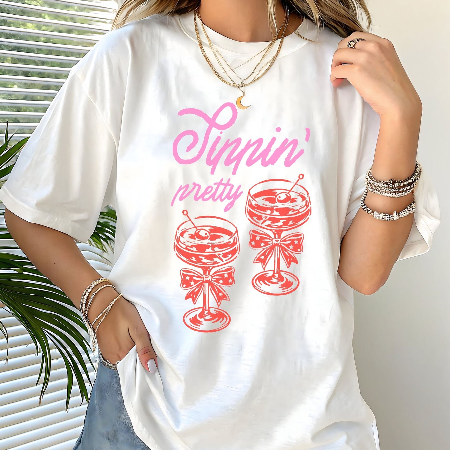Vintage style t-shirt with “Sippin' Pretty” text and two illustrated coupe cocktail glasses with bows