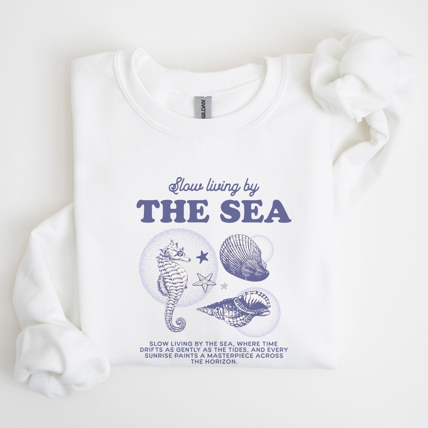 Vintage-style seahorse and seashell graphic with “Slow Living by the Sea” text on a soft unisex sweatshirt, part of the summer coastal collection.