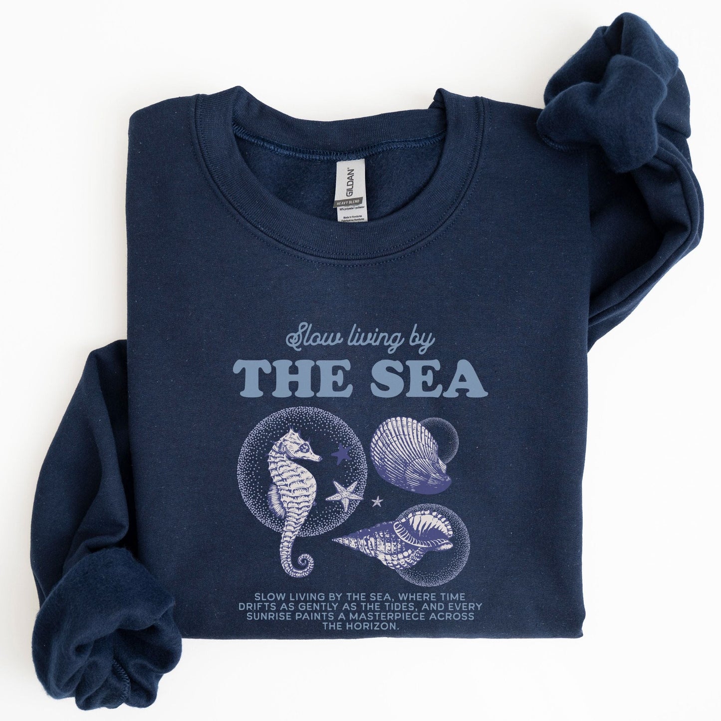 Vintage-style seahorse and seashell graphic with “Slow Living by the Sea” text on a soft unisex sweatshirt, part of the summer coastal collection.