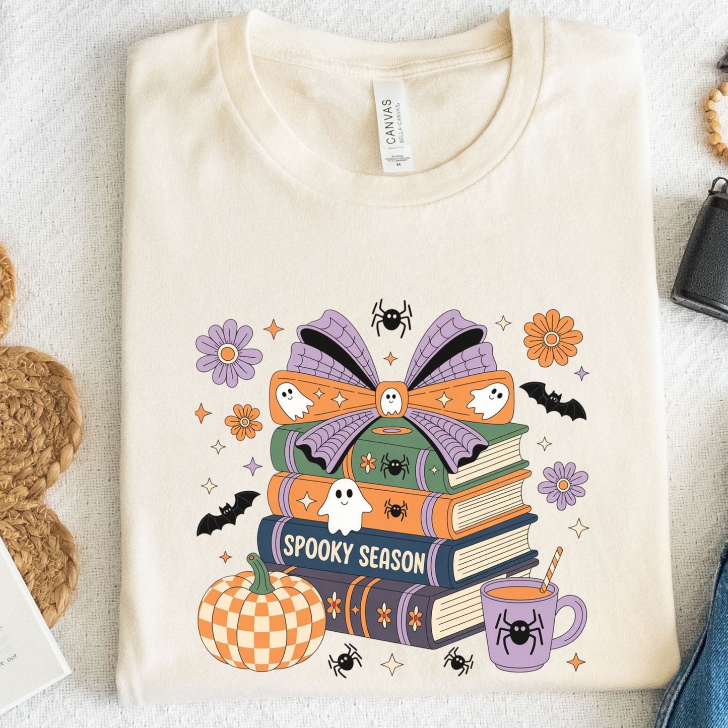Halloween t-shirt with colorful stack of books, ghosts, pumpkin, and coffee cup reading “Spooky Season.”