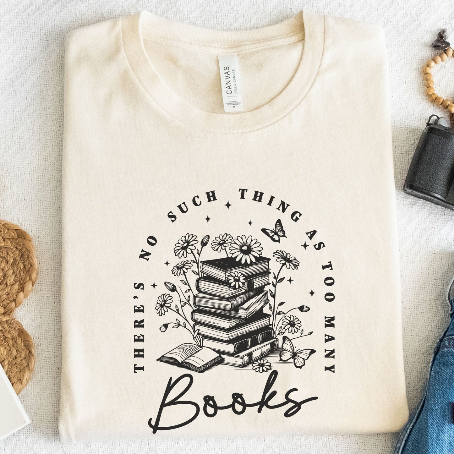 “Too Many Books, Not Enough Time” t-shirt with minimalist stacked books and handwritten lettering in black line art style.