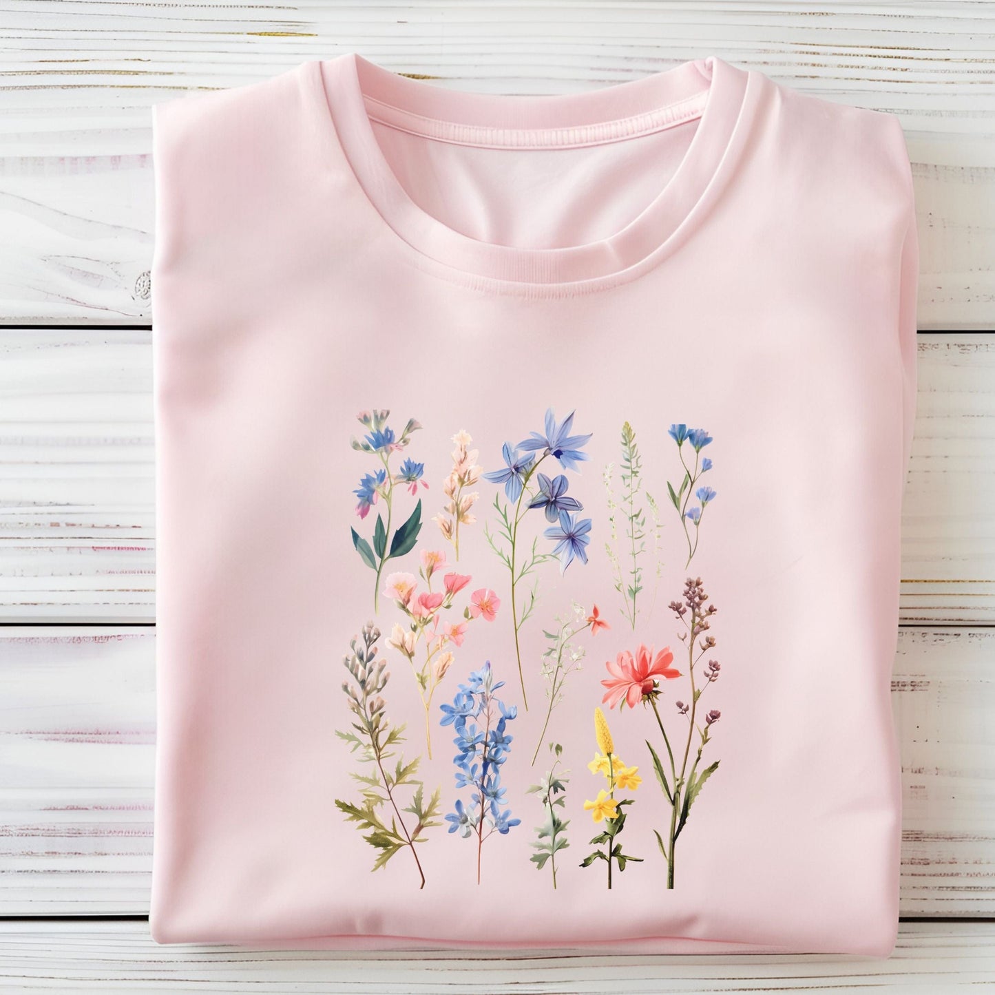 Vintage wildflower t-shirt featuring hand-drawn pastel florals in soft pinks, blues, and yellows arranged in a scattered botanical layout.