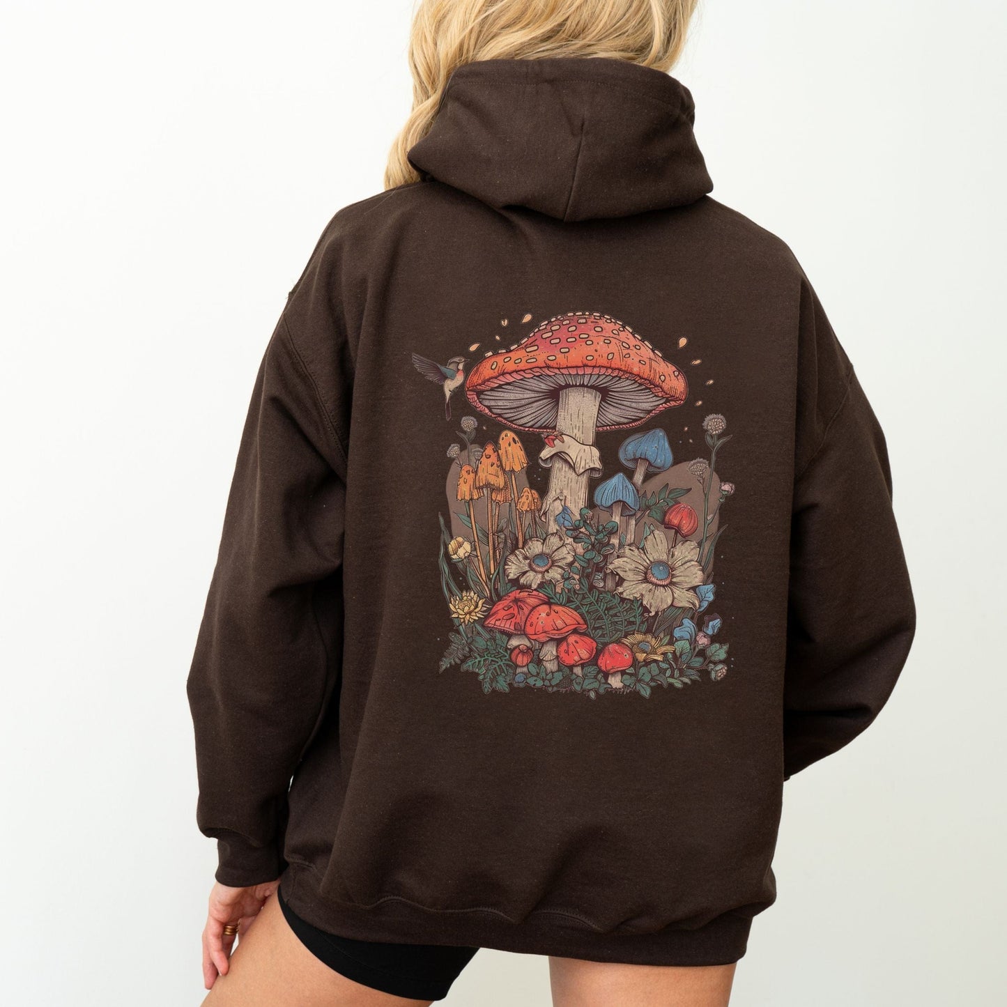 Back hoodie design featuring whimsical mushrooms, wildflowers, and a hummingbird in a cottagecore spring forest setting