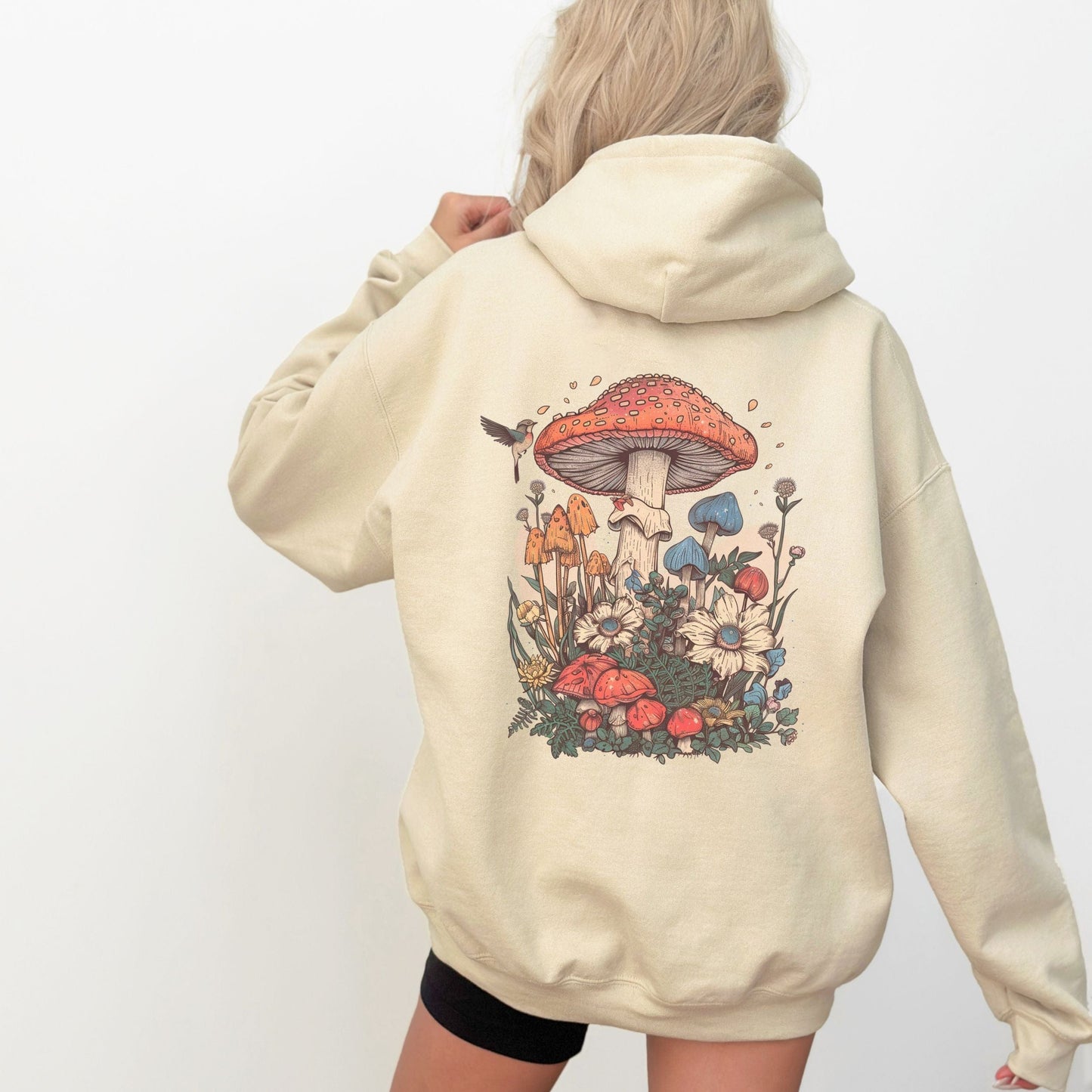 Back hoodie design featuring whimsical mushrooms, wildflowers, and a hummingbird in a cottagecore spring forest setting