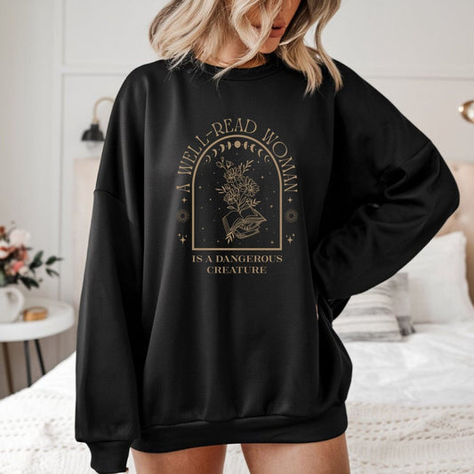 A Well-Read Woman sweatshirt featuring celestial symbols, wildflowers, and stacked books in a mystical vintage style — perfect for book lovers and feminists.