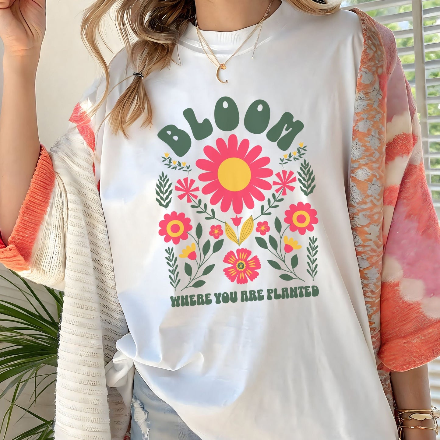“Bloom Where You Are Planted” t-shirt with bold retro florals and uplifting message in green, pink, and yellow tones.