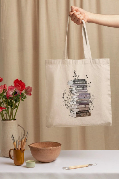 Cotton canvas tote bag with floral book stack design, perfect book lover gift.