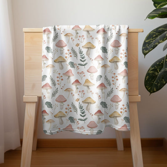 Pastel mushroom baby blanket with botanical woodland design for nursery decor.