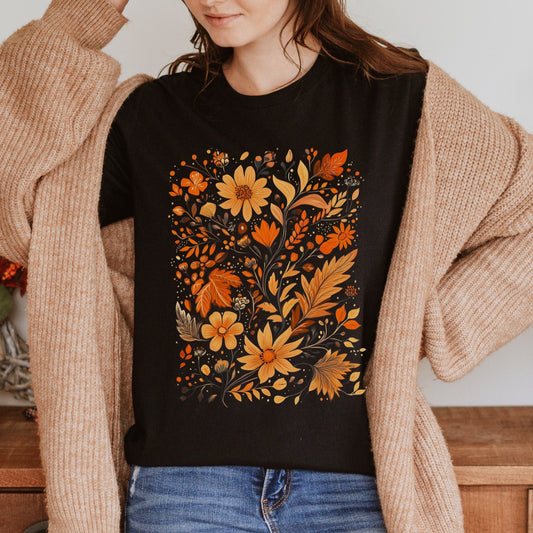T-shirt with autumn floral design in orange, yellow, and brown featuring hand-drawn leaves, petals, and wildflowers