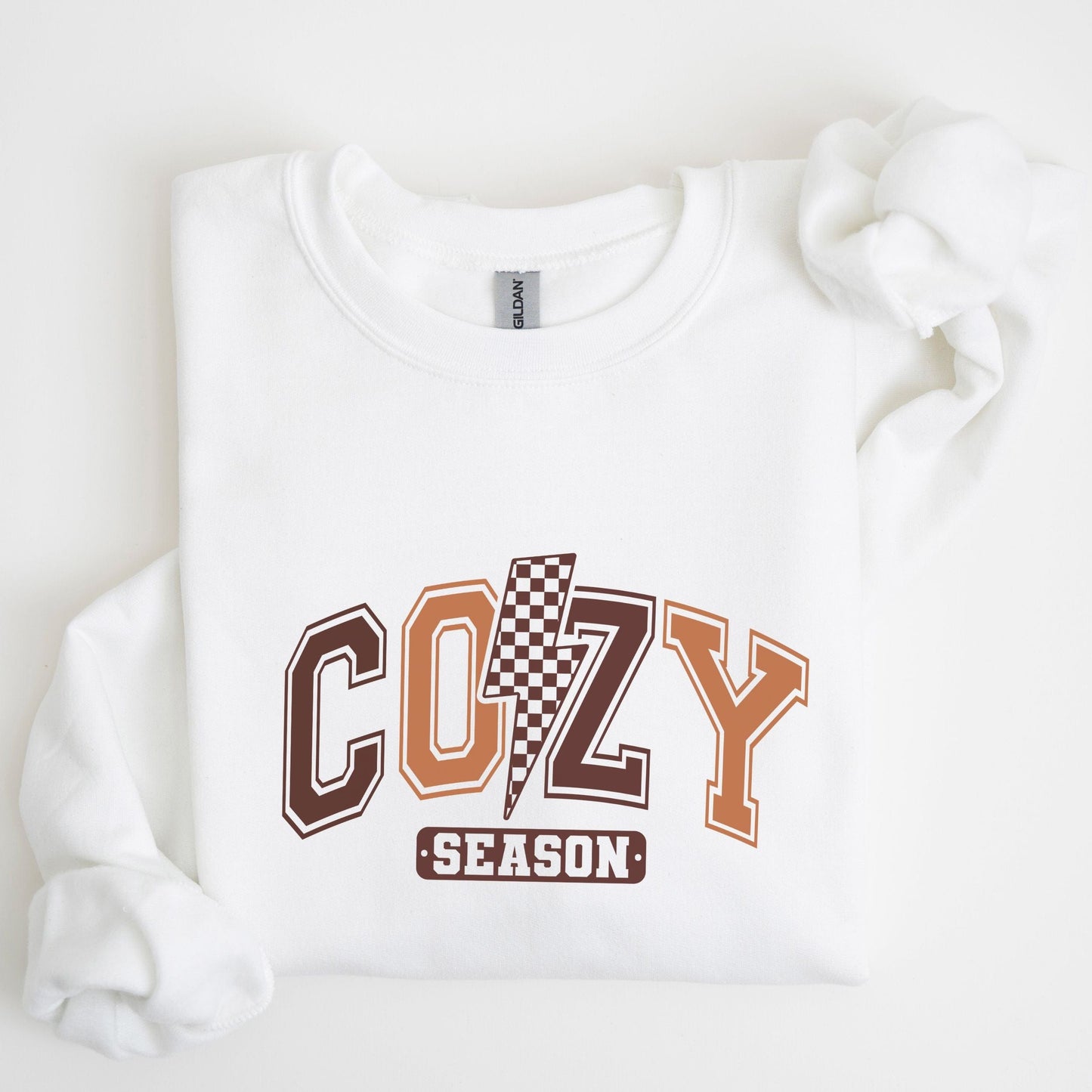 Cozy Season sweatshirt with retro varsity letters in fall colors and a checkered lightning bolt—perfect autumn apparel for cozy vibes.