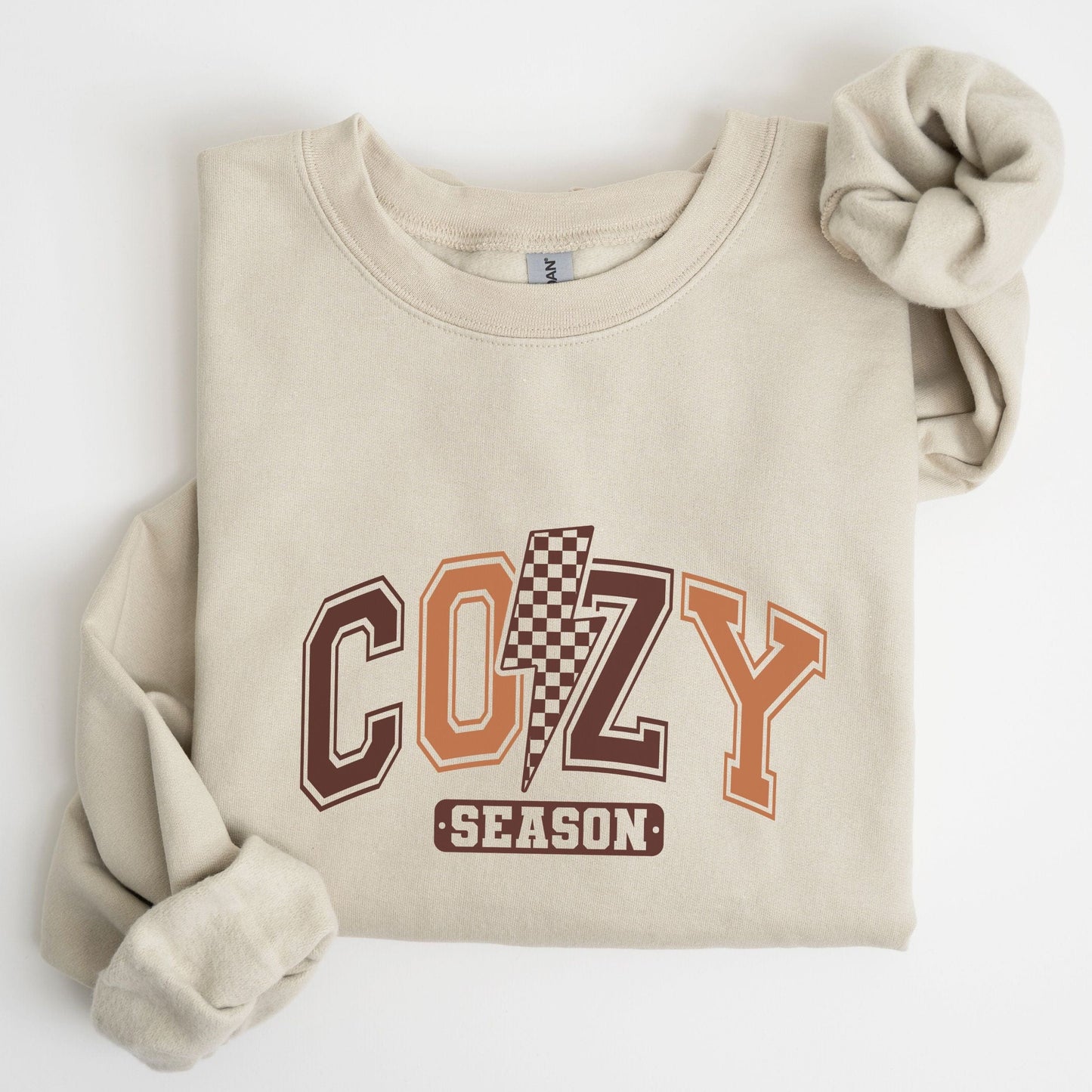 Cozy Season sweatshirt with retro varsity letters in fall colors and a checkered lightning bolt—perfect autumn apparel for cozy vibes.