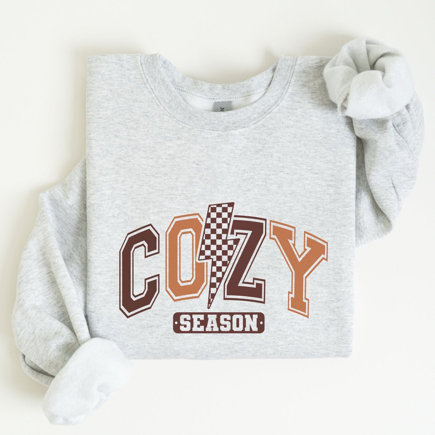 Cozy Season sweatshirt with retro varsity letters in fall colors and a checkered lightning bolt—perfect autumn apparel for cozy vibes.