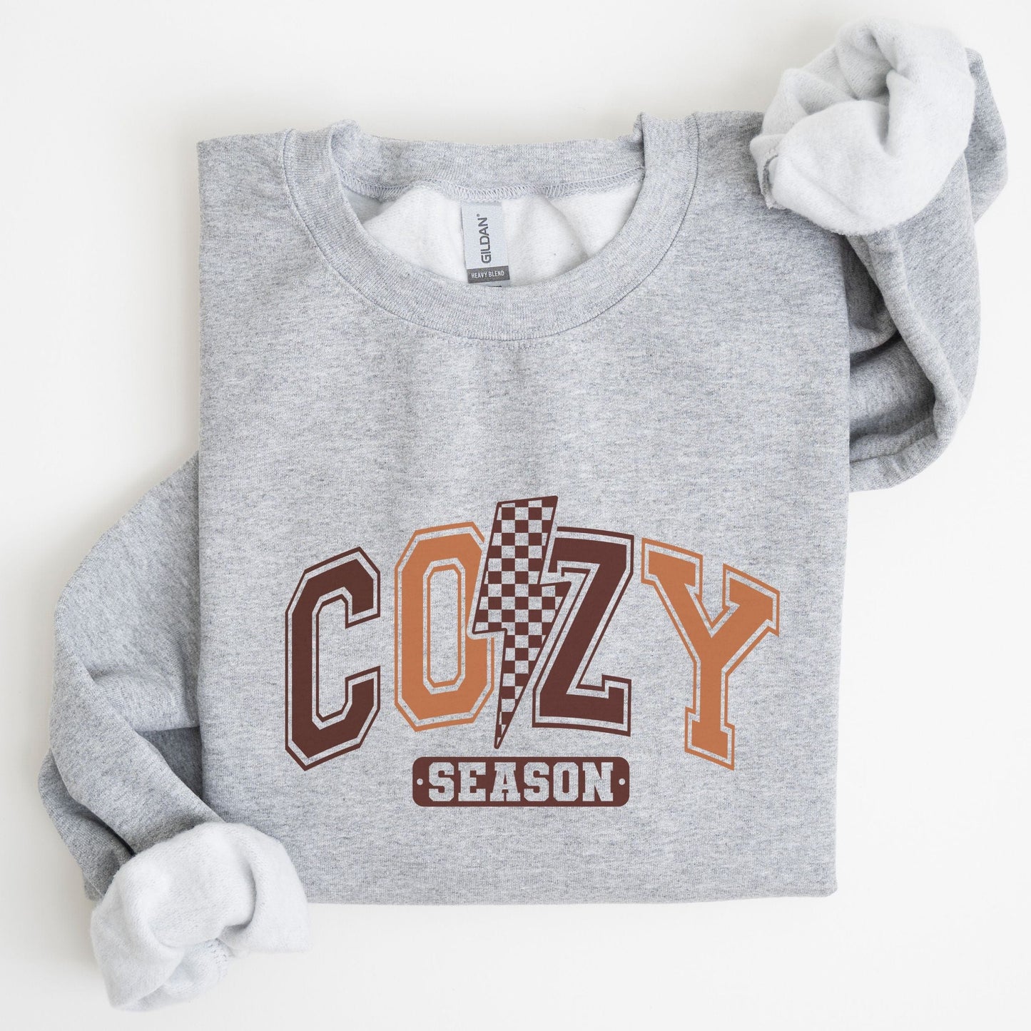 Cozy Season sweatshirt with retro varsity letters in fall colors and a checkered lightning bolt—perfect autumn apparel for cozy vibes.