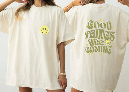 Good Things Are ComingGood Things Are Coming shirt, Y2K-inspired streetwear, retro typography, smiley faces. Shirt Printify