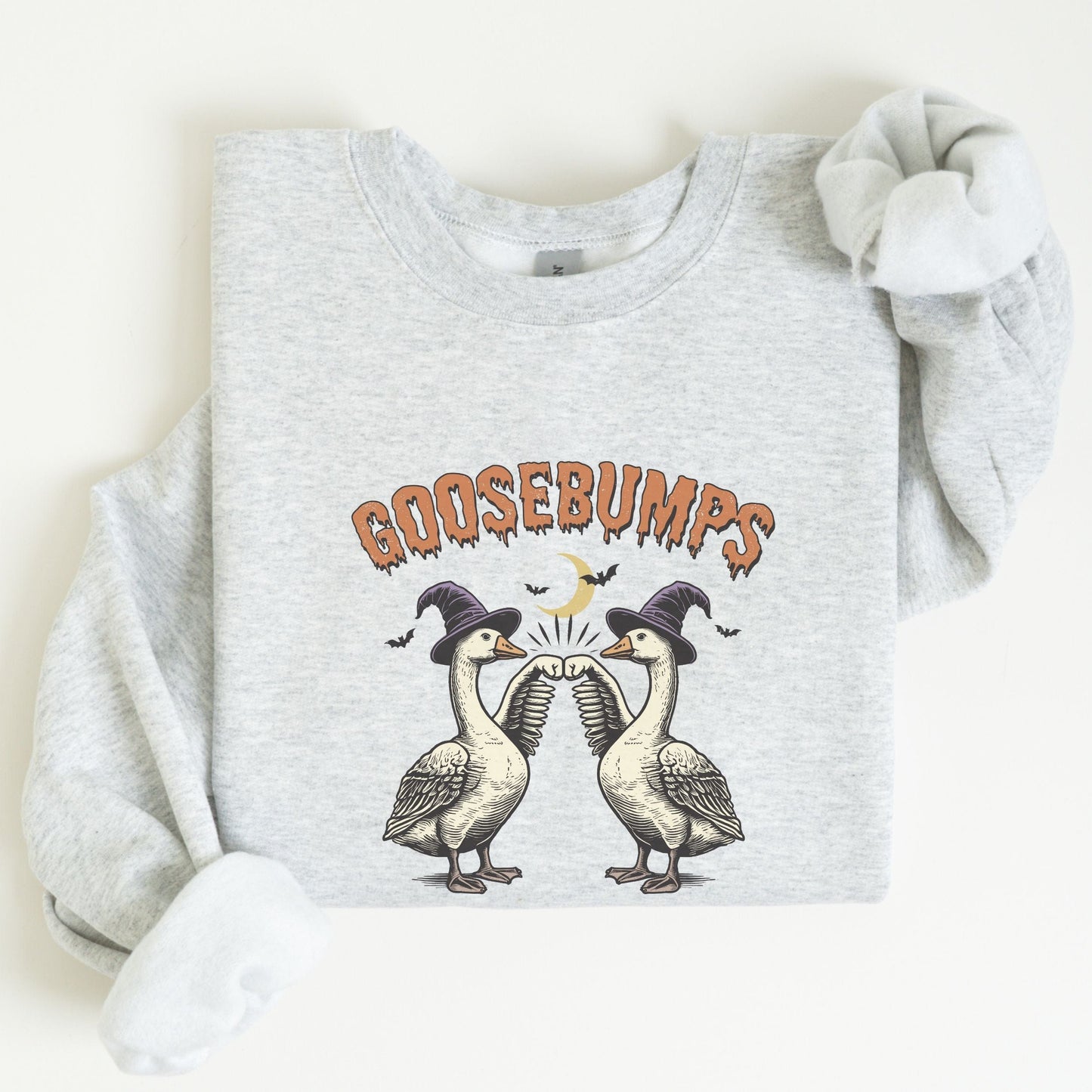 Halloween sweatshirt with two geese in witch hats bumping wings under a crescent moon — spooky and fun fall apparel.