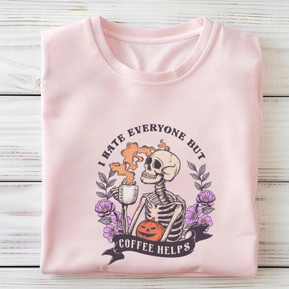 “I Hate Everyone But Coffee Helps” t-shirt with skeleton drinking coffee, purple flowers, jack-o’-lantern, and gothic Halloween design.