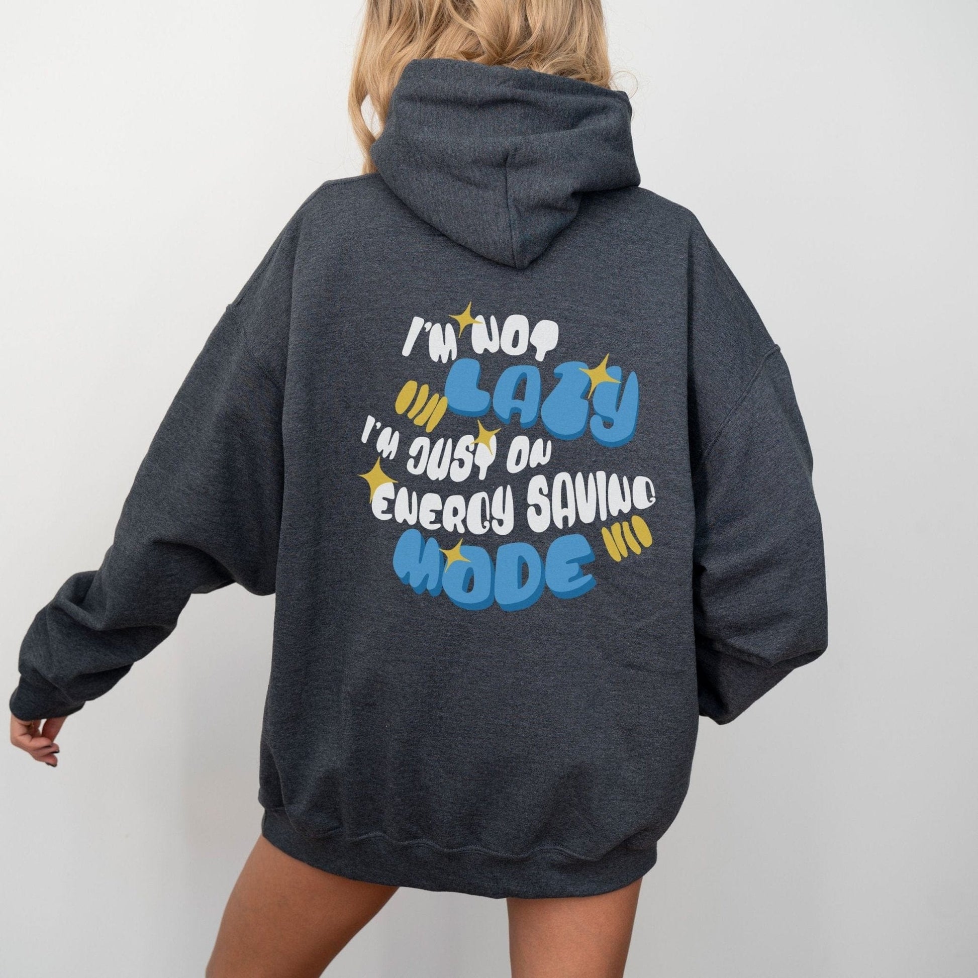 Back of a hoodie with the phrase “I’m Not Lazy, I’m Just on Energy Saving Mode” in playful retro typography. Cozy, unisex fit.
