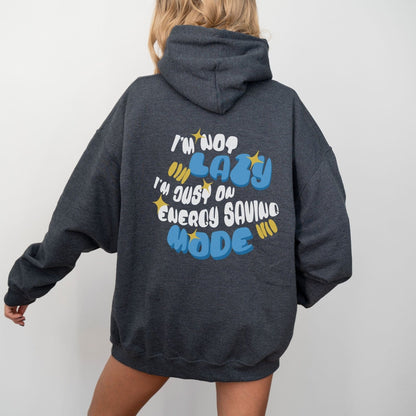 Back of a hoodie with the phrase “I’m Not Lazy, I’m Just on Energy Saving Mode” in playful retro typography. Cozy, unisex fit.